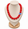 Red beaded necklace with powder blue heart accent on jewelry display